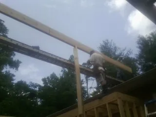 Carpenter setting a ridge beam over a new addition frame — Ice Dam Removal by Roofing Brothers in Mount Sinai