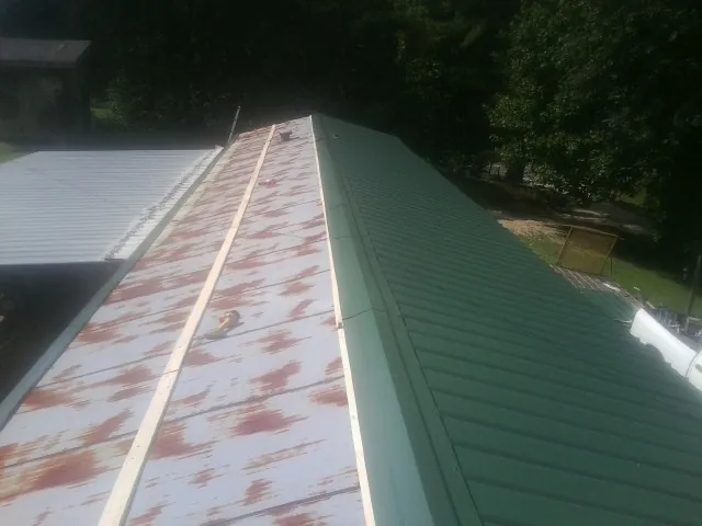 Old rusted panels beside newly installed green metal roofing — Wind Damage Roof Repair by Roofing Brothers in Mount Sinai