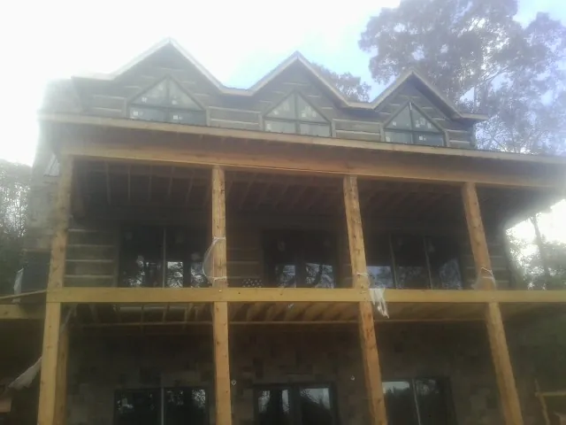 Dormers and porch framing on a large log home under construction — Roof Coating work by our crew in Mount Sinai