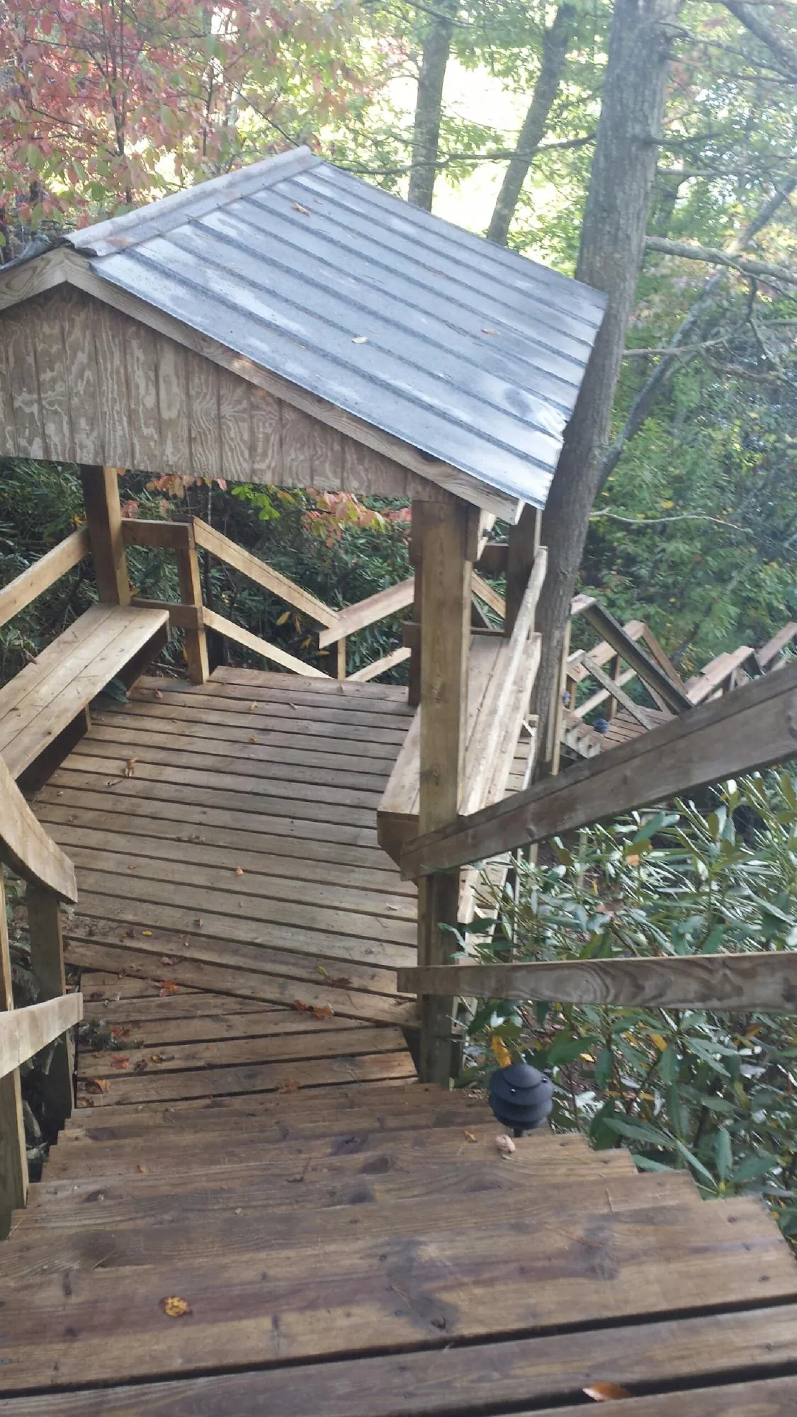 Metal roofed shelter over wooden steps on a wooded walkway — Skylight Repair & Installation work by our crew in Mount Sinai