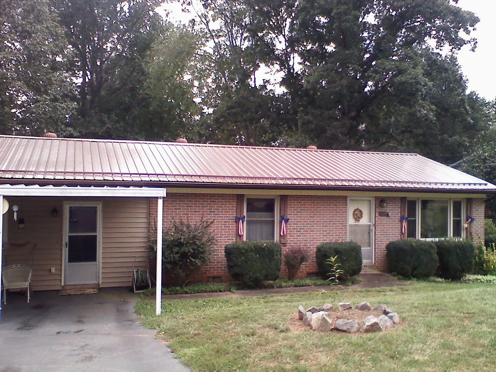 Bronze metal roof and carport on a brick ranch home — Roof Repair work by our crew in Mount Sinai