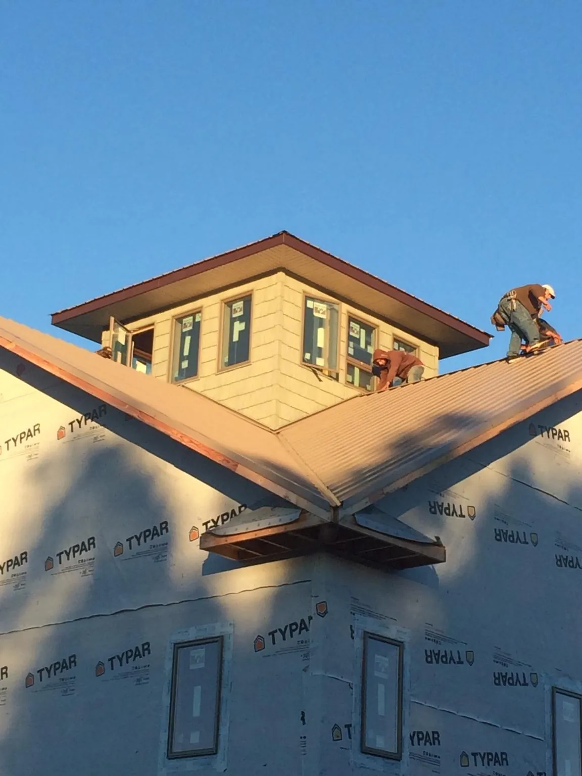 Roofers working around a rooftop cupola on a new metal roof at sunset — Roof Waterproofing in Mount Sinai by Roofing Brothers